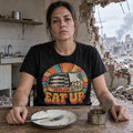 EAT UP sardine tin retro graphic on a black T-shirt, worn by a woman in a damaged kitchen